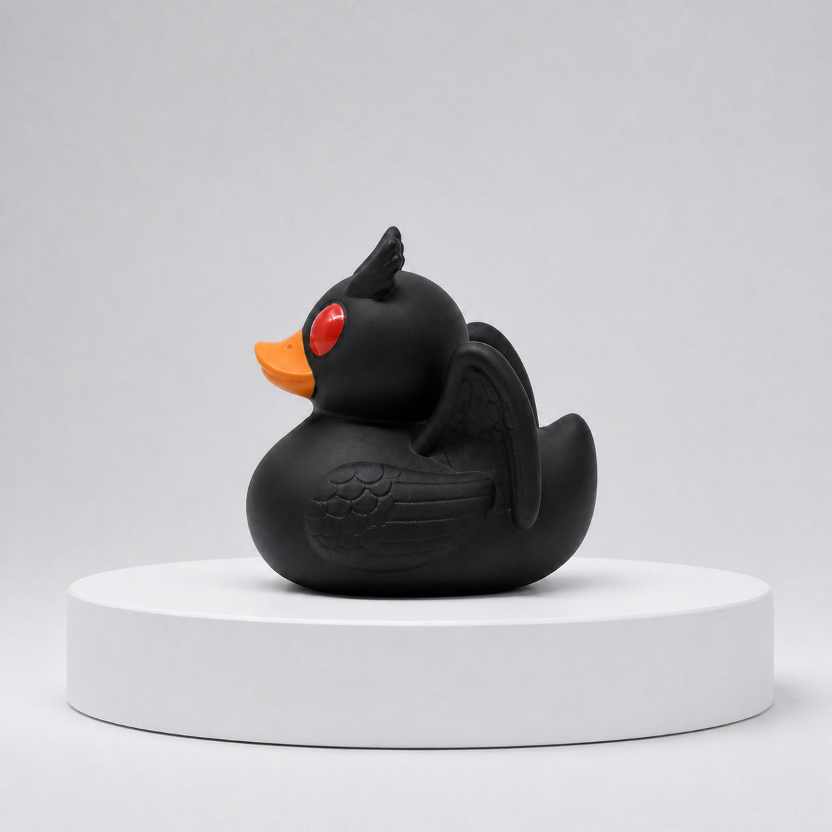 Side view of the Orange Bill Mothduck, a Mothman-inspired rubber duck with a black body, bright orange bill, red eyes, horns and wings.
